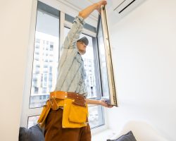 Construction worker installing window in house.