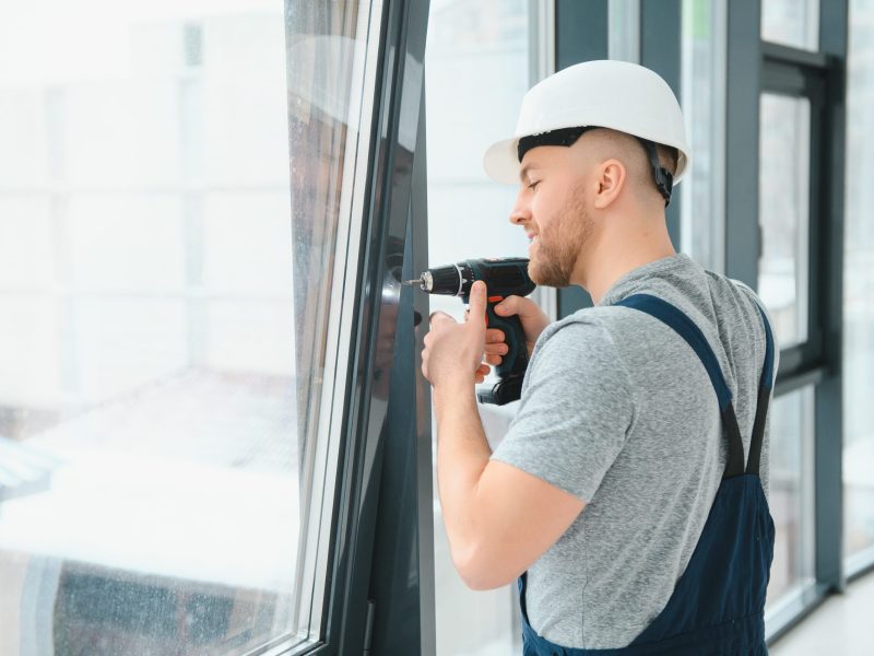 handsome young man installing bay window in new house construction site