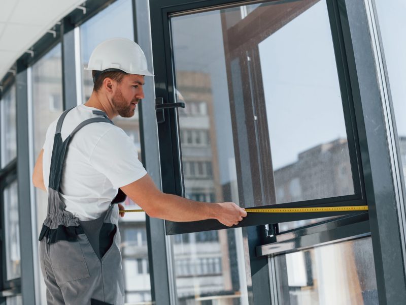 Holding window. Repairman is working indoors in the modern room commercial window replacement fairless hills pa