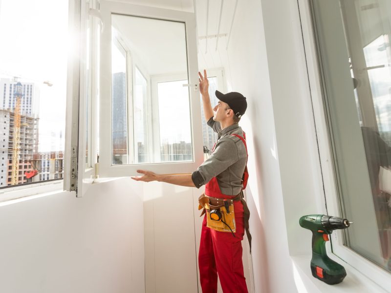 Worker sealing plastic window with caulk indoors. Installation process Worker sealing plastic window with caulk indoors. Installation process. High quality photo